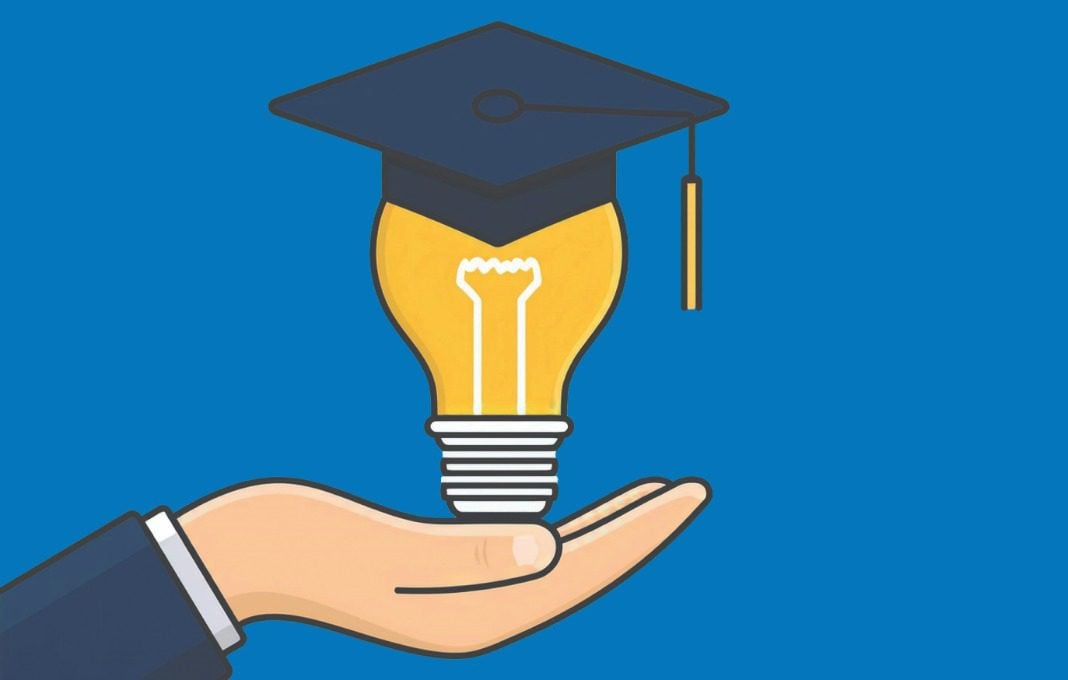 Hand holding a lightbulb with a graduation cap on top
