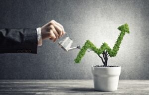 Hand watering a tree in the shape of an arrow pointing up