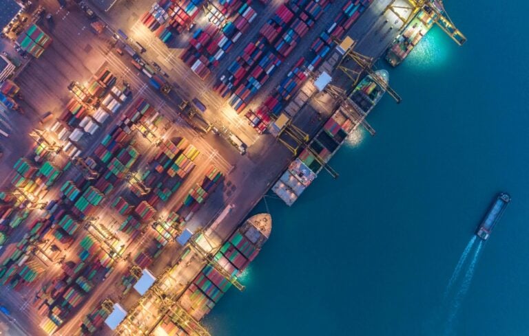 Container ship in export and import business and logistics. Shipping cargo to harbor by crane. Water transport International. Aerial view