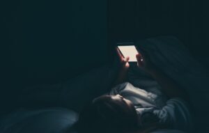 Woman scrolling on phone in the dark
