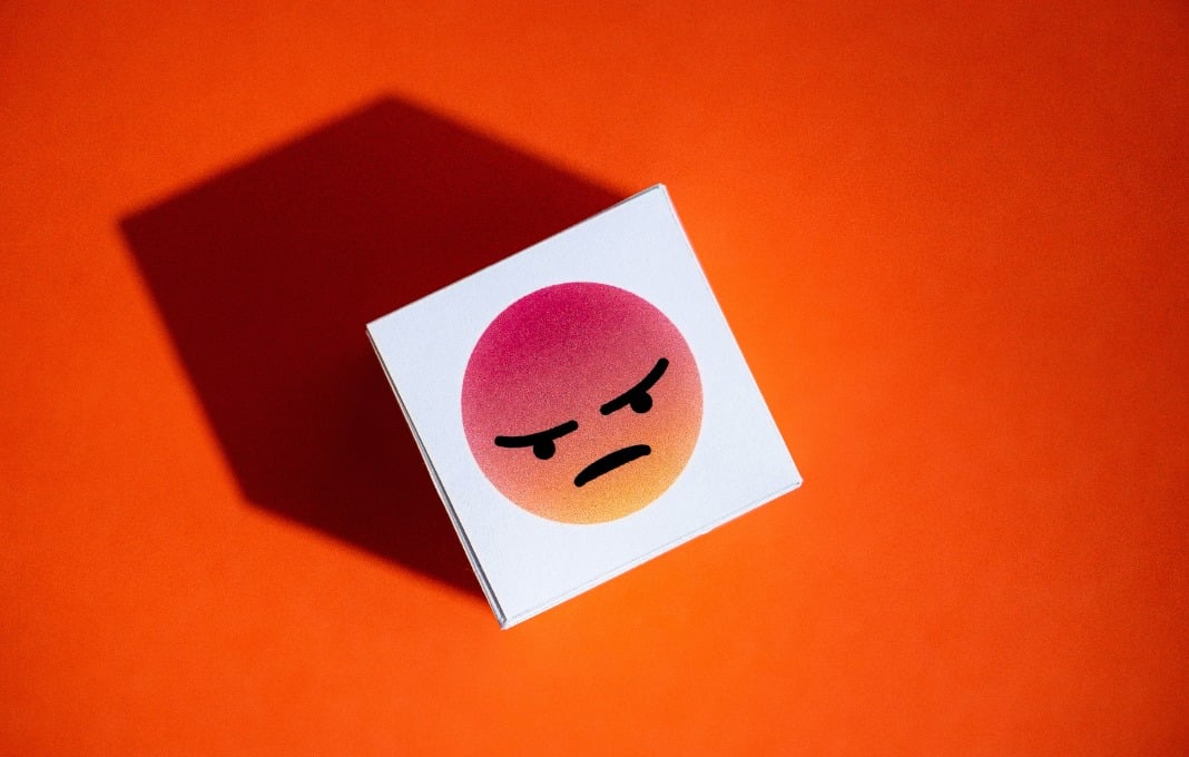 An anger emoji symbol from Facebook Messenger printed on a paper cube.