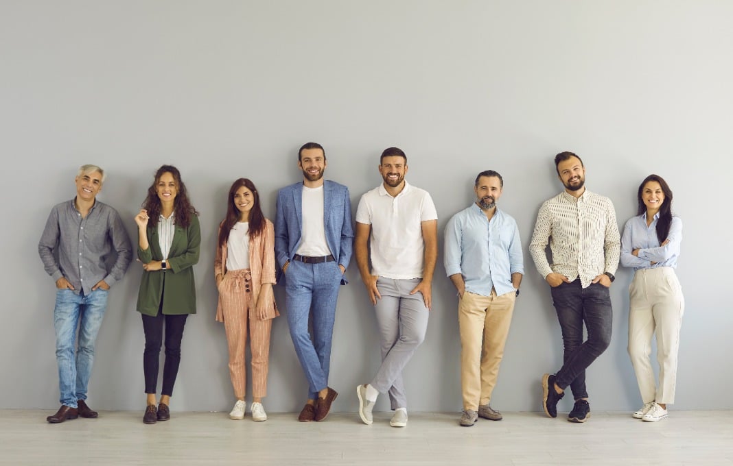 Group of people standing, smiling against wall